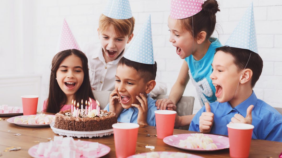 Kids birthday party. Boy blowing out candles on cake