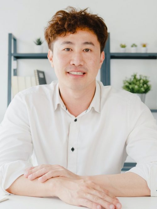 Asian businessman using laptop talk to colleagues in video call meeting while working from home.
