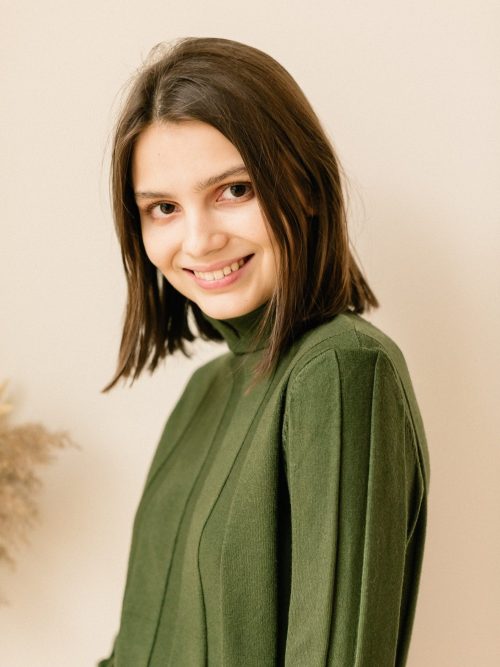 Studio portrait of a young woman in sweater on beige background.