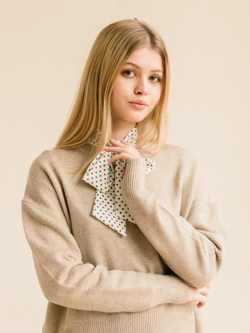 Studio portrait of a young woman in the dress on beige background.