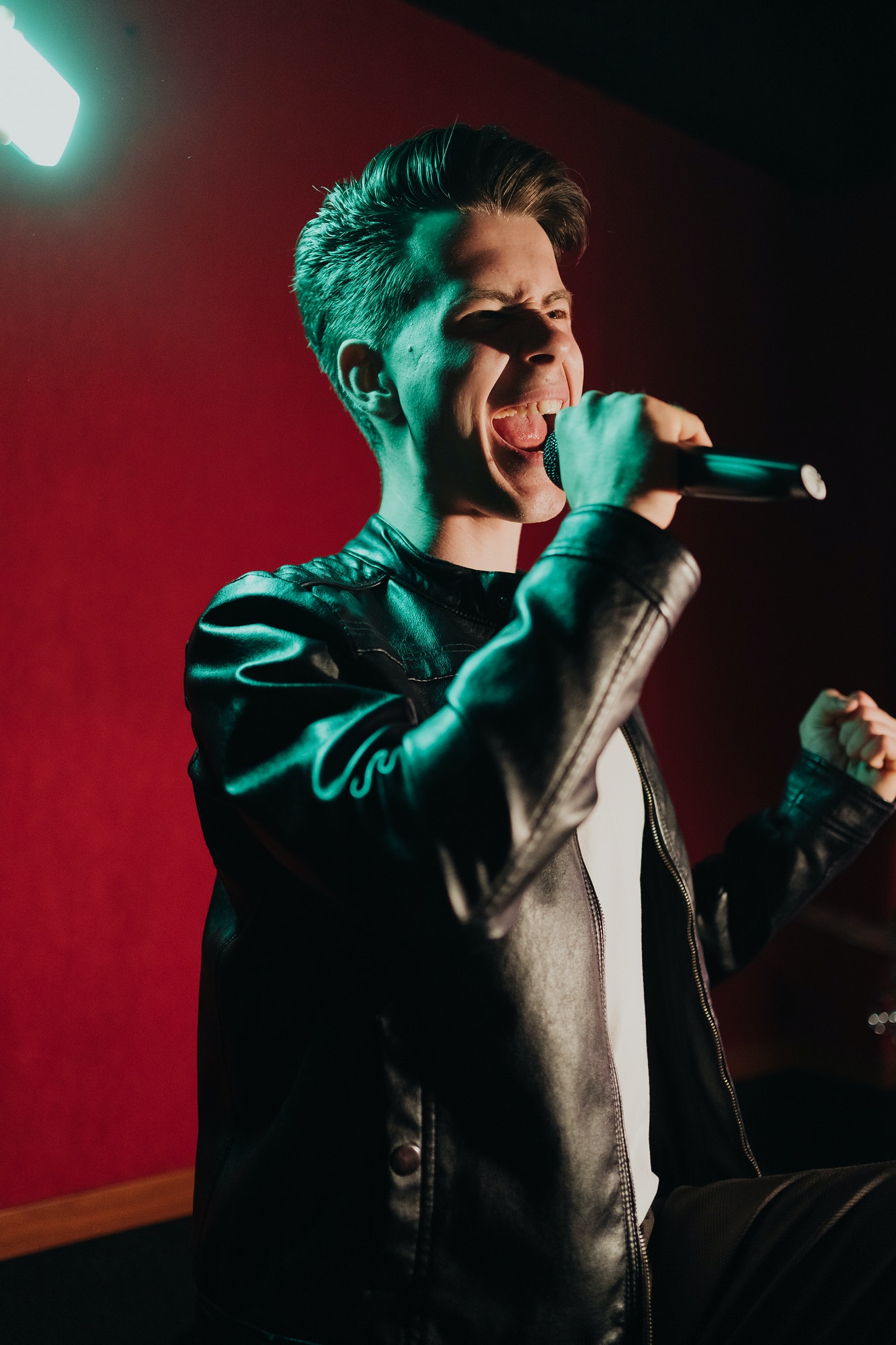 Man in leather jacket performing on a dark stage in club